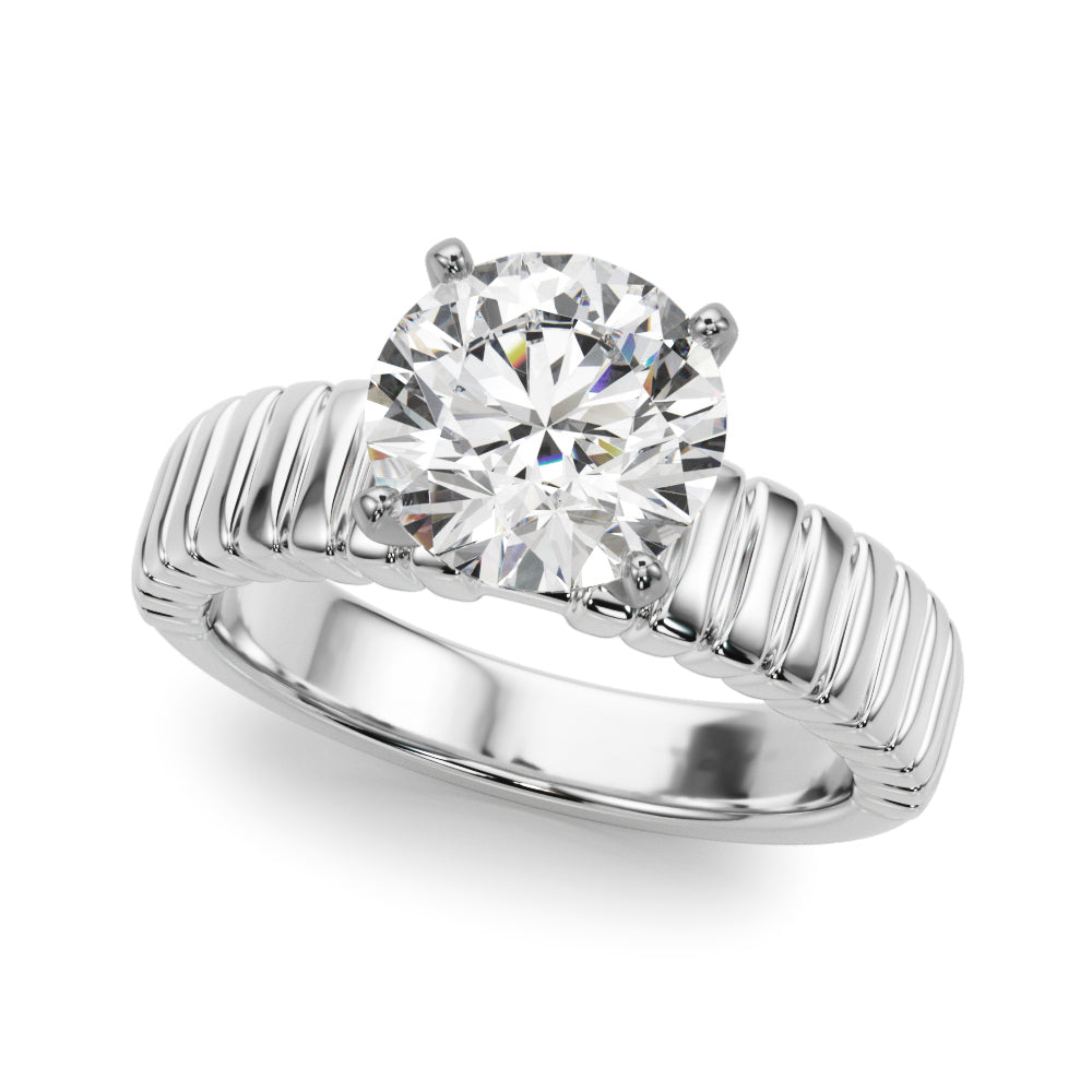 A white gold engagement ring with a large, round diamond sits on a white background. The ring features intricate ridged details on the band, conveying elegance.