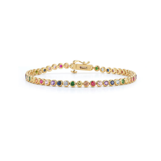 A delicate gold tennis bracelet featuring multicolored rainbow bezel gemstones is displayed on a white background, creating an elegant and luxurious appearance.
